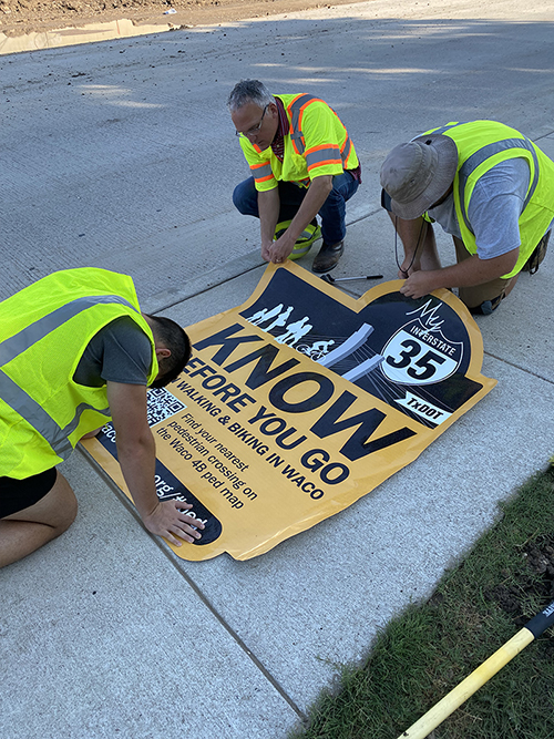 Workers prepare a know-before-you-go decal for installation